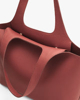 Leather tote bag with curvy design and shoulder straps.