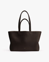 Large tote bag with long handles shown on plain backdrop.