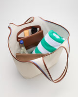 Open tote bag with a towel, bottle, and various items inside.