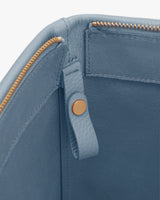 Close-up of a purse with zipper and button detail.