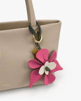 Handbag with a keychain featuring a pink and white flower design.
