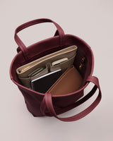 Open handbag with organized items inside, including a laptop and notebook.