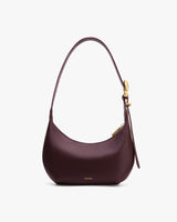 Handbag with curved shape and single strap on plain background
