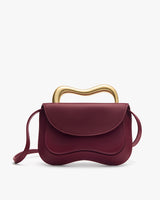 Handbag with wavy metallic handle and long strap.