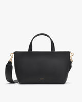 Handbag with top handles and a shoulder strap, standing upright.