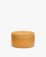 Round leather zippered case on a plain background.