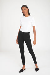 Woman in a T-shirt and leggings standing in a studio.