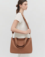 Woman standing with a large shoulder bag.