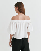 Woman in off-shoulder top and pants facing away from camera