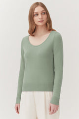 Woman in a sweater standing, looking to her right.
