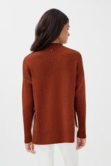 Woman in a long sleeve top standing with her back facing the camera.