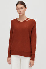 Woman in a sweater standing against a plain background.