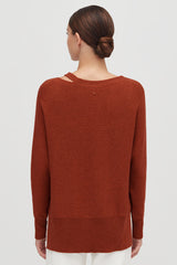 Woman facing away, wearing a sweater and styled hair in a bun.
