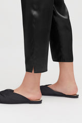 Person wearing cropped pants and flat shoes standing.