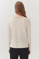 Rear view of a woman wearing a sweater and pants, standing.