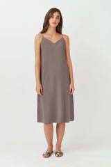 Person standing in a sleeveless knee-length dress and sandals.
