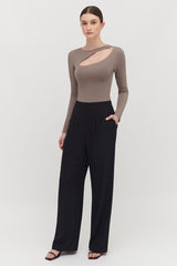 Woman standing in a long sleeve top and trousers.