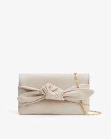 Clutch purse with a bow and chain strap on white background.