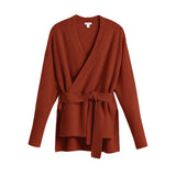 Sweater with a wrap design and belt on a plain background.