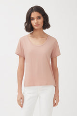 Woman in a plain t-shirt and pants standing against a white background.