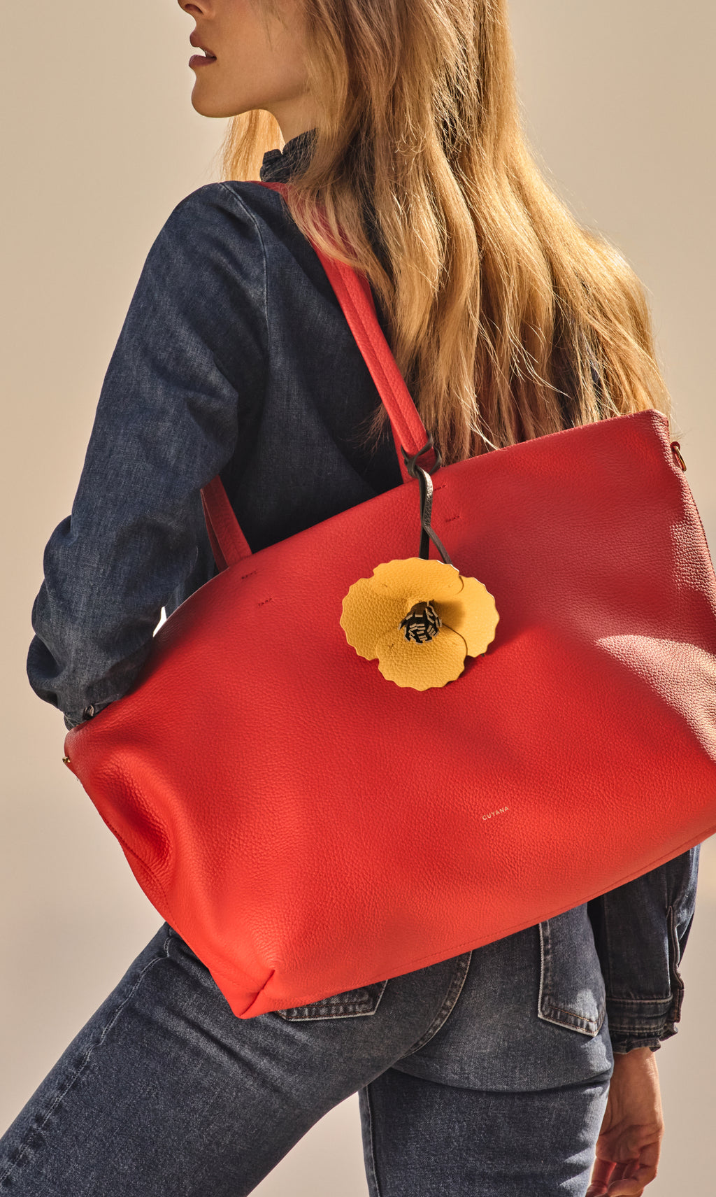 Person carrying a large travel bag with a floral accessory.
