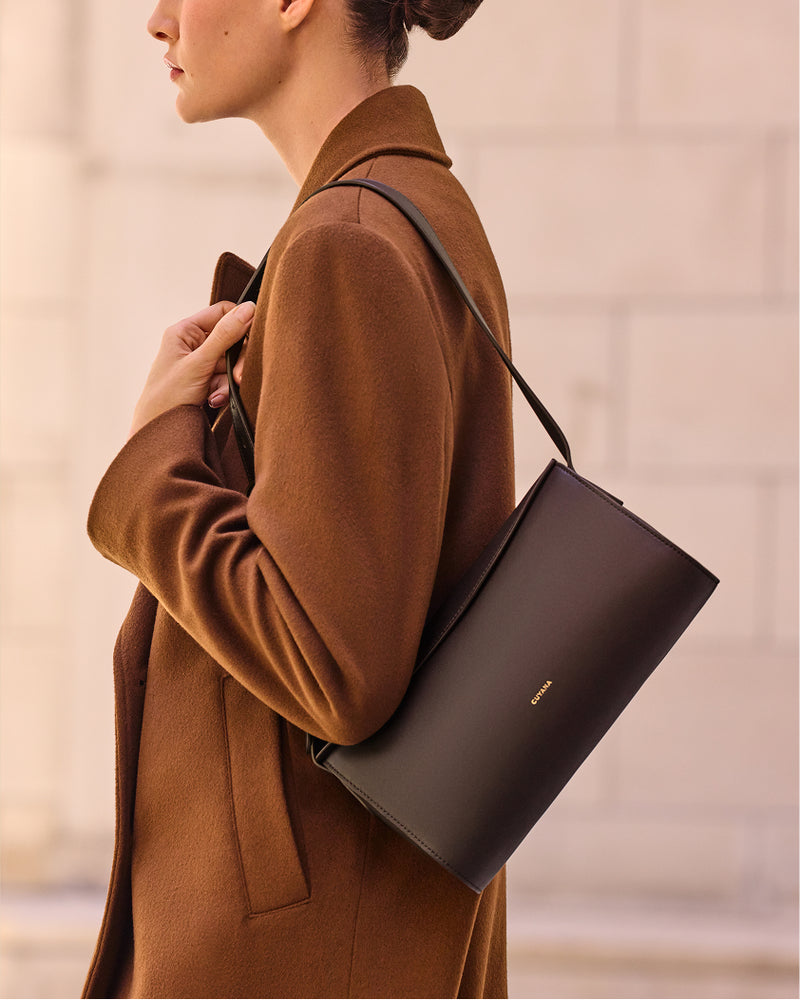 Person wearing a coat holding a shoulder bag.