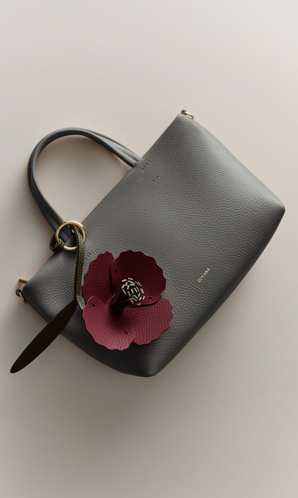 Handbag with large flower decoration and small logo near the top.