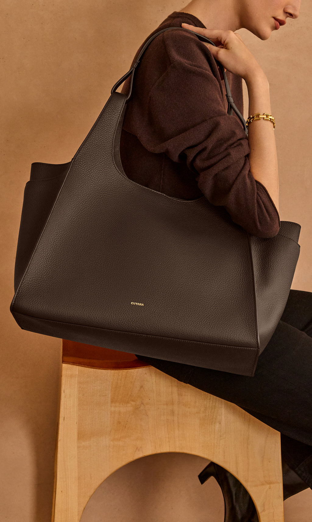 Person sitting with large tote bag on shoulder.