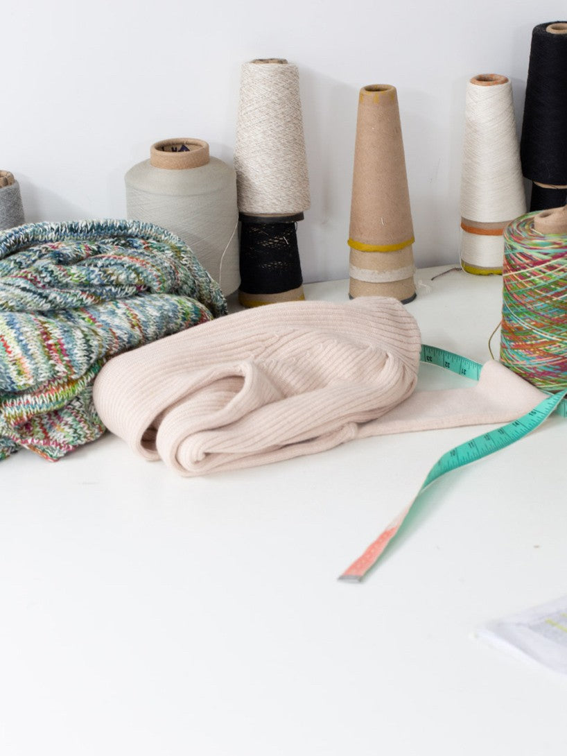Yarn spools, sweater, and measuring tape on a table