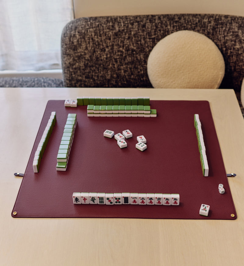 Mahjong game setup on a table with tiles on a mat.