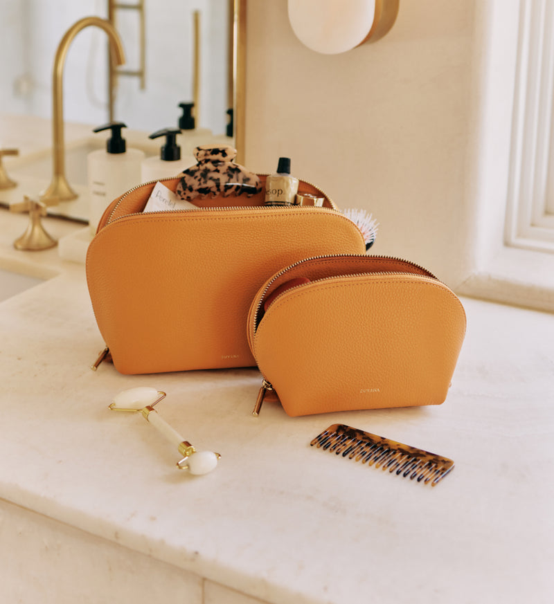 Two toiletry bags on a bathroom counter with grooming items.
