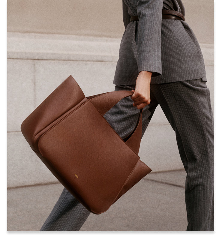 Person walking with a large tote bag, wearing a suit.