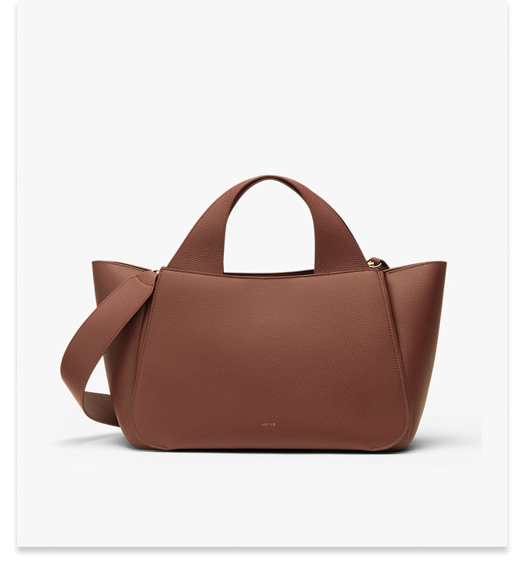 Handbag with two handles and a shoulder strap on display.