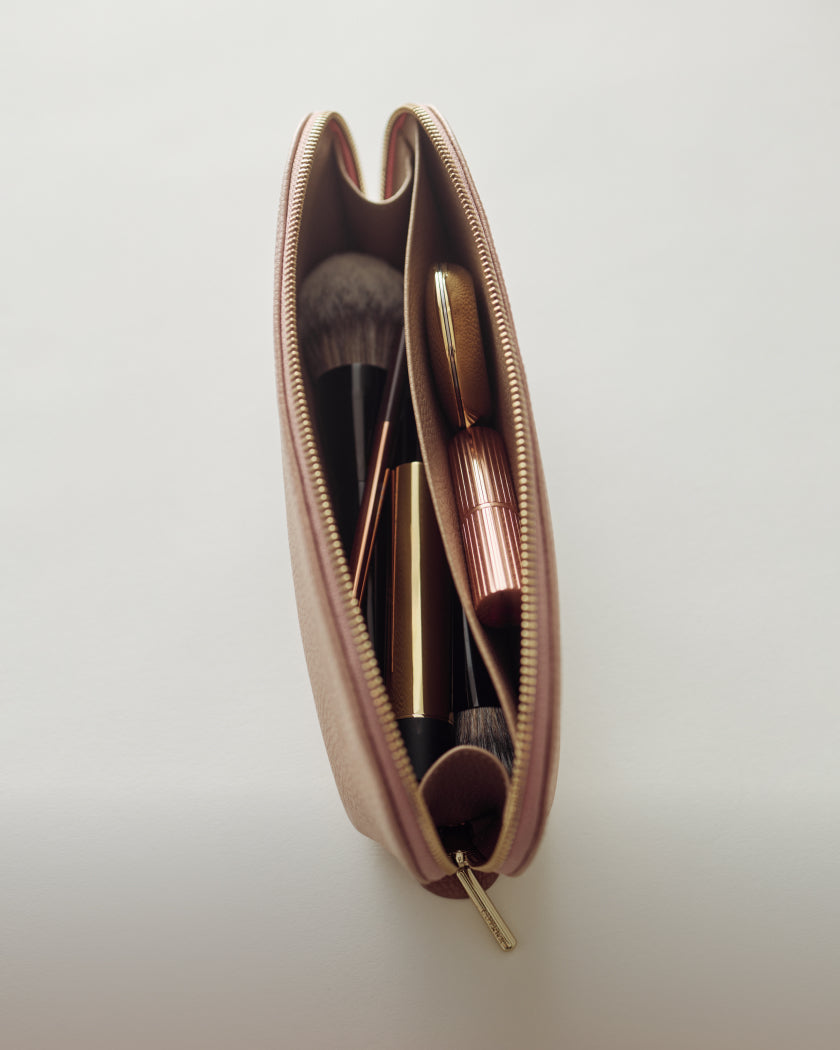 Open makeup bag with brushes and a lipstick inside.