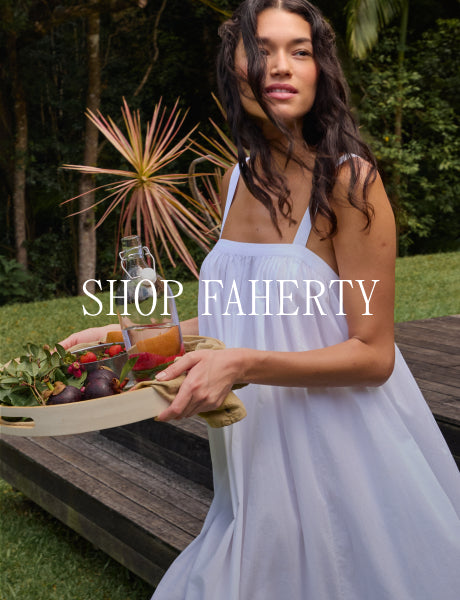 Woman holding a food tray on a patio with plants in background.
