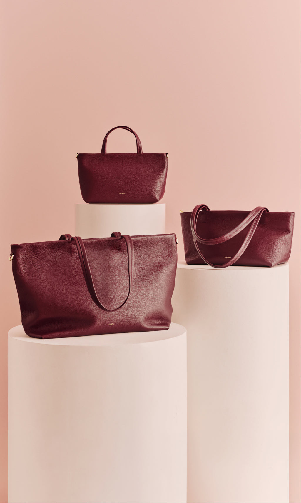 Three handbags displayed on white pedestals.