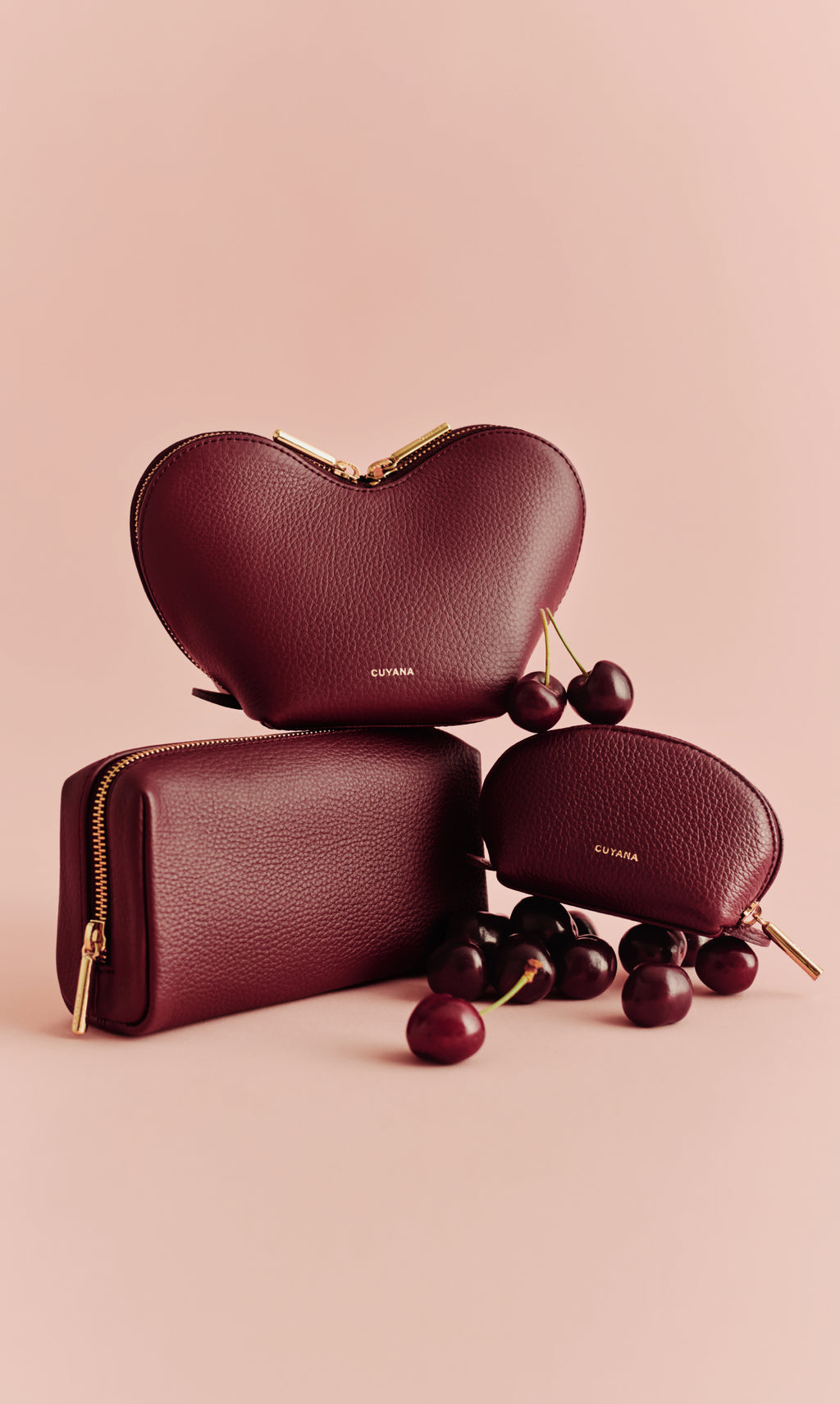 Three leather pouches with cherries on a neutral background.