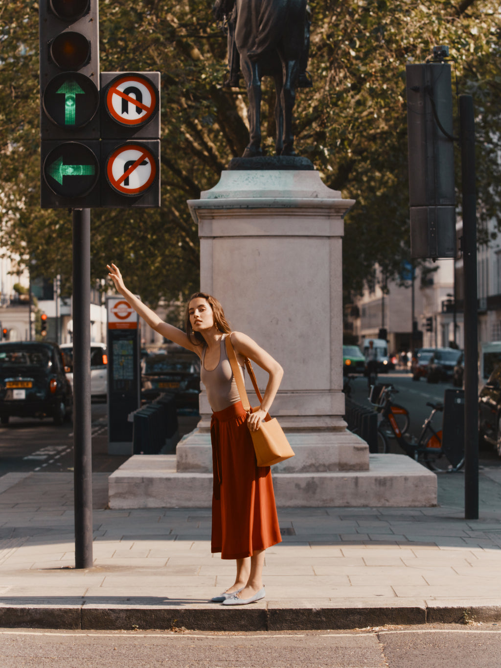 Woman hailing a taxi near traffic lights and a statue