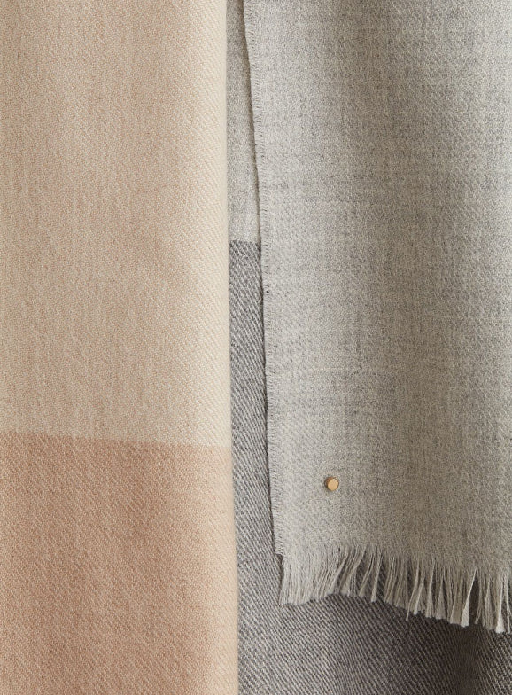 Two hanging textiles with fringe at bottom edges.