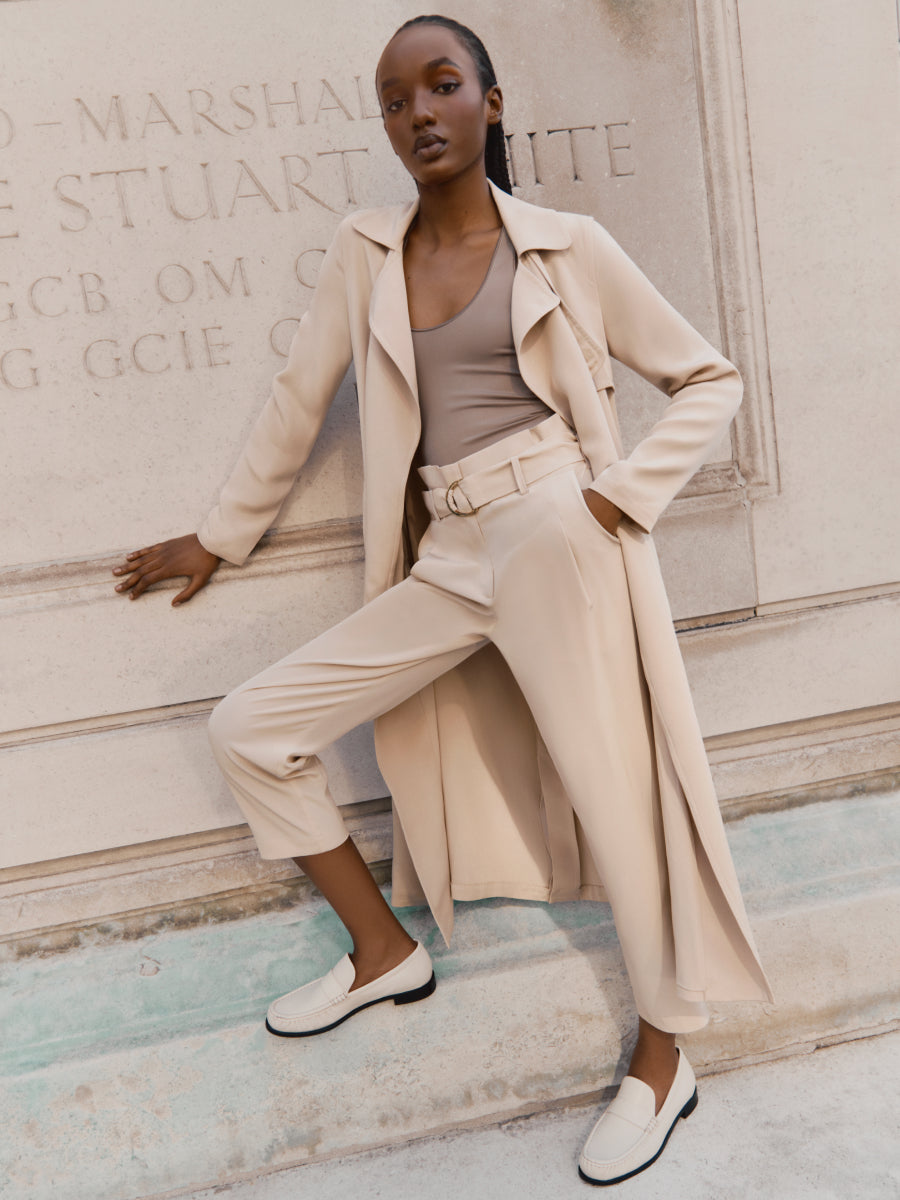 Woman posing by a stone wall in stylish outfit
