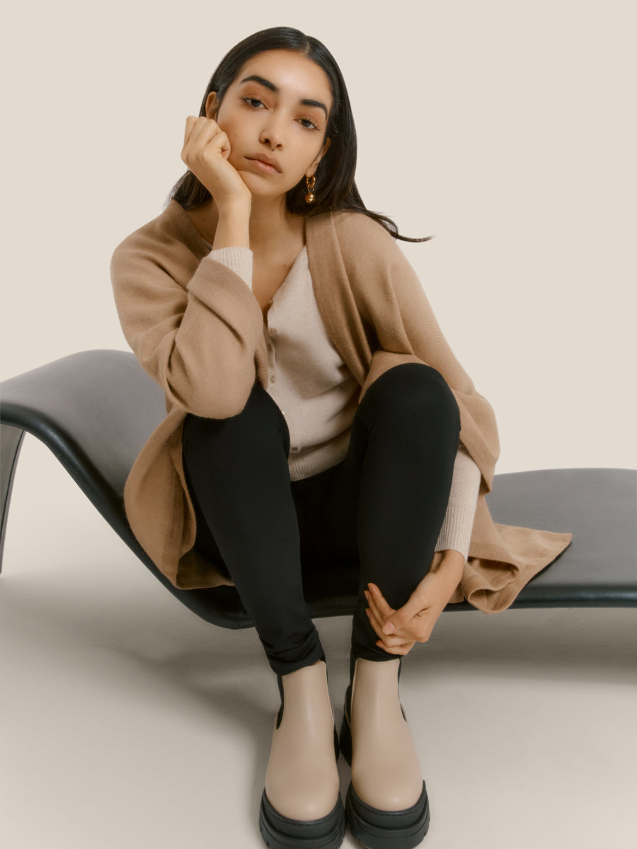 Woman sitting on a curved chair resting her cheek on her hand.
