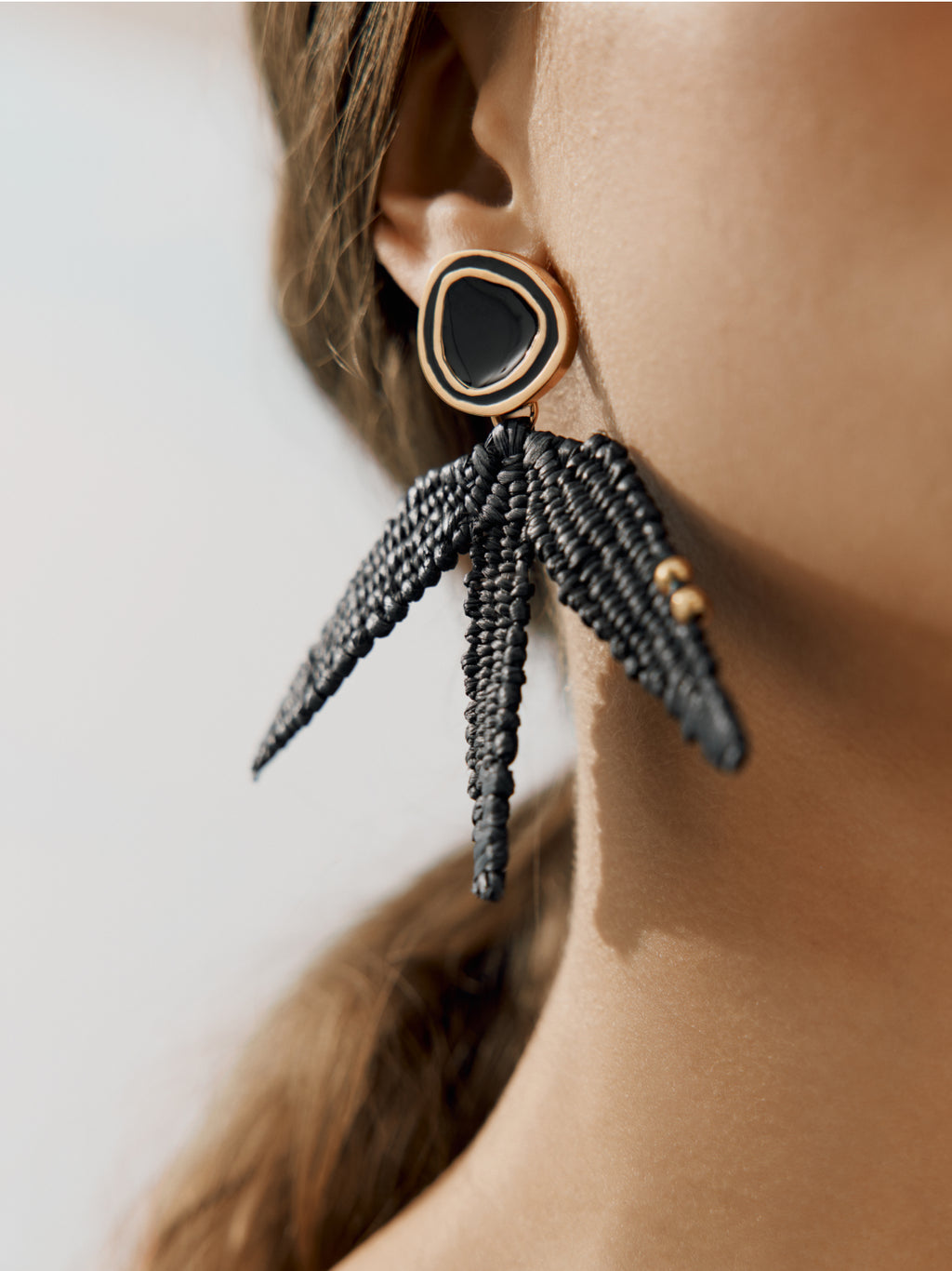 Woman wearing woven earrings with beaded tassels