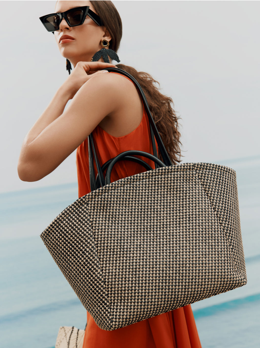 Person with large tote bag by the ocean.