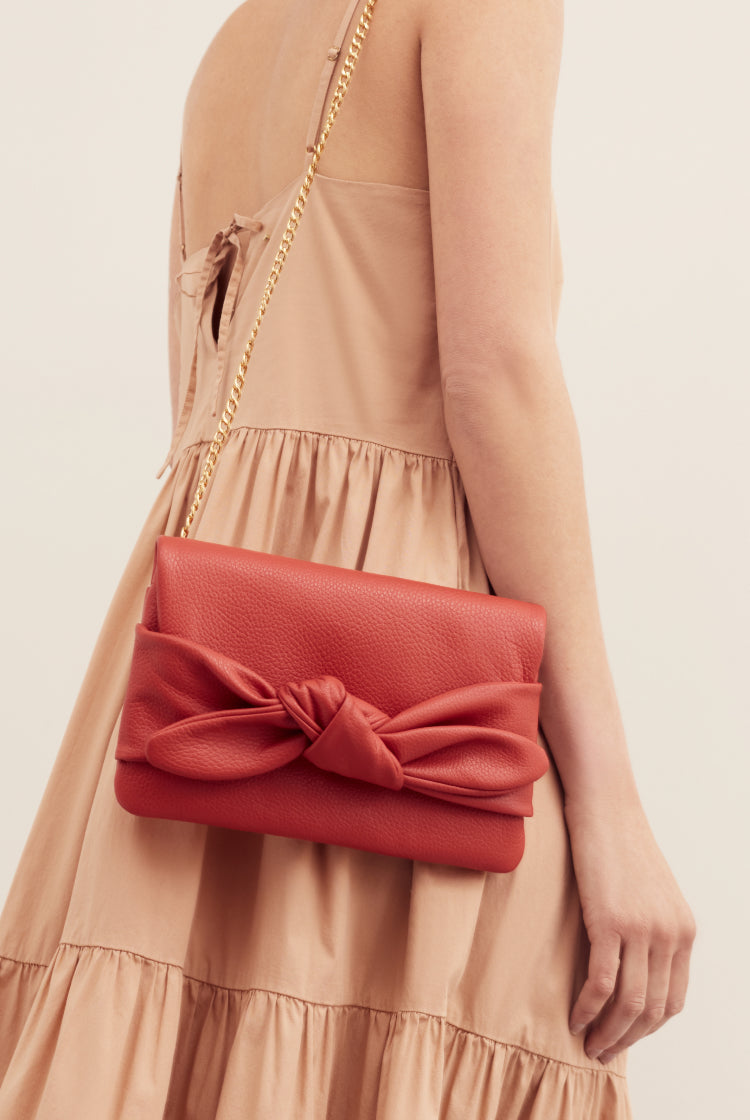Woman holding a purse with a bow over her shoulder.