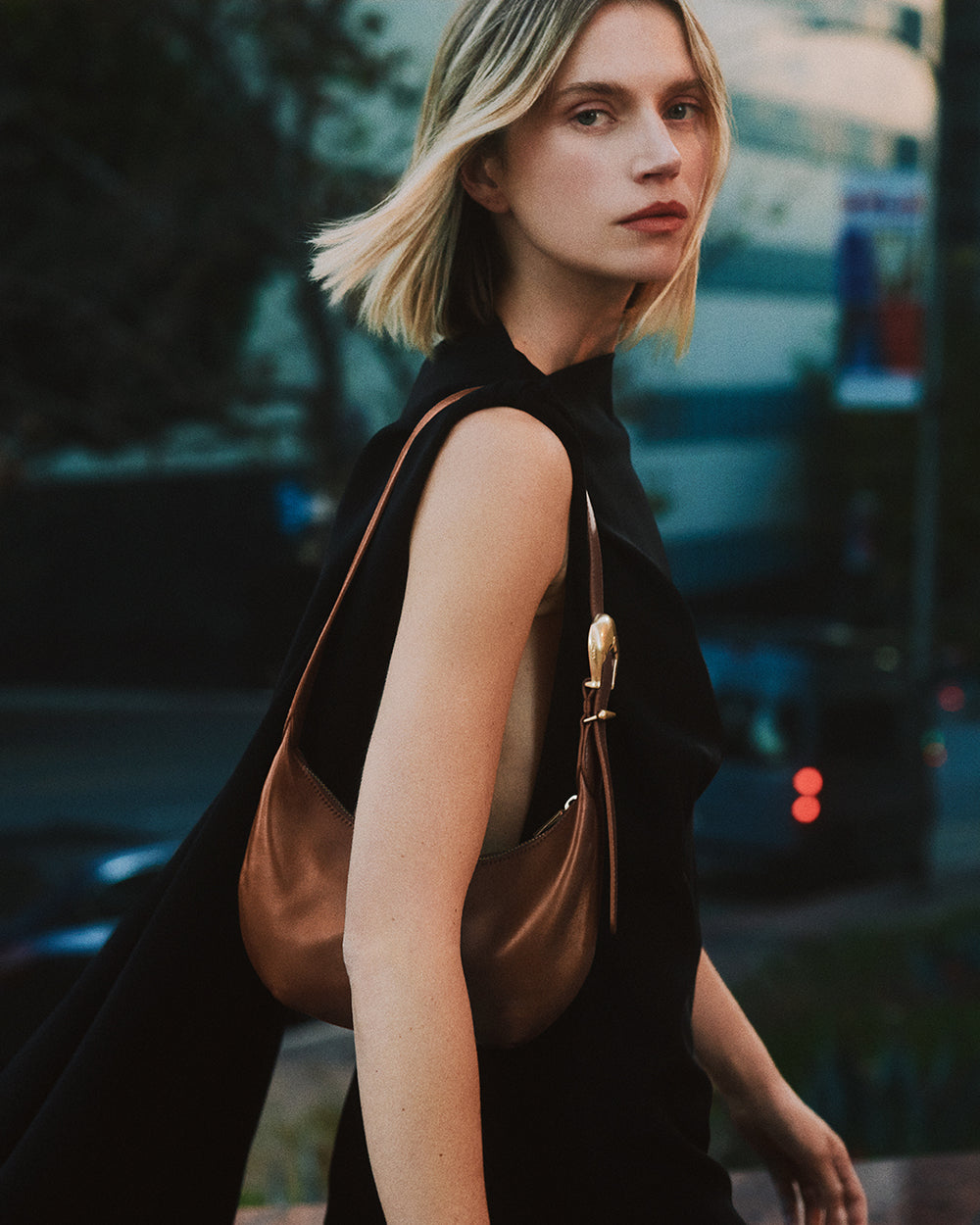 Person wearing a sleeveless top and holding a shoulder bag.