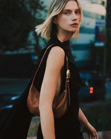 Person wearing a sleeveless top and holding a shoulder bag.