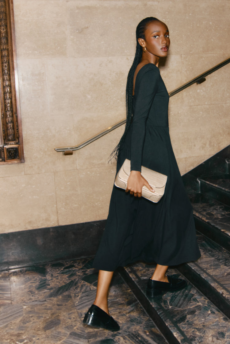 Woman walking down stairs holding a clutch bag.