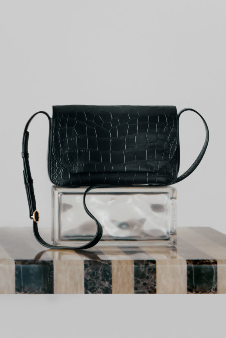 Purse on top of a clear box on a striped surface.