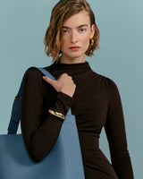 Woman with short hair carrying a large bag, looking at camera.