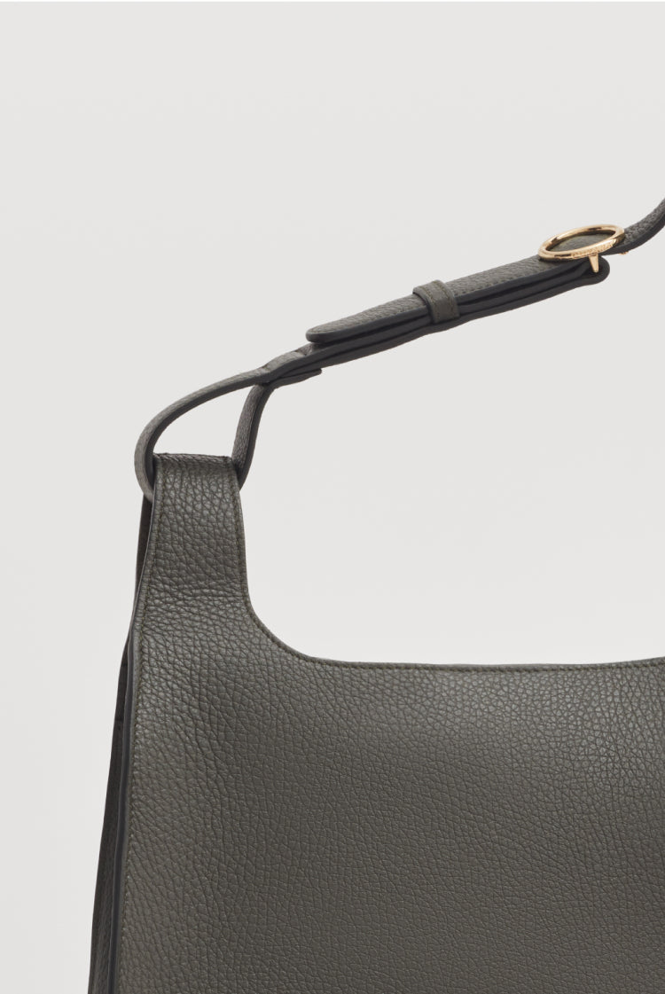 Close-up of a handbag with a shoulder strap and metal clasp.